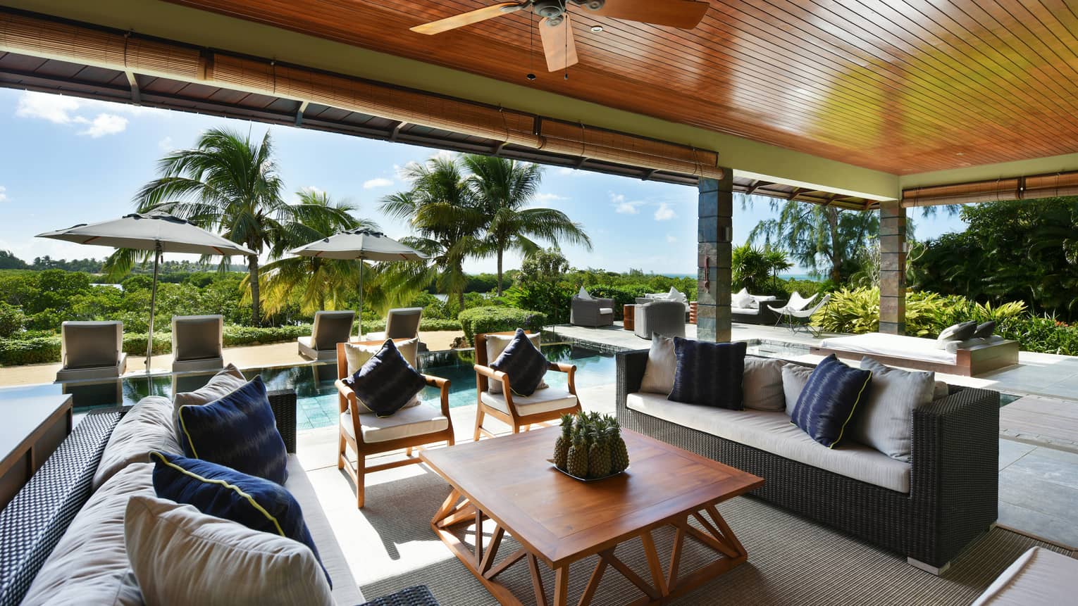 Grand Residence Villa long wicker sofas, wood furniture under wood roof, lounge chairs lining pool