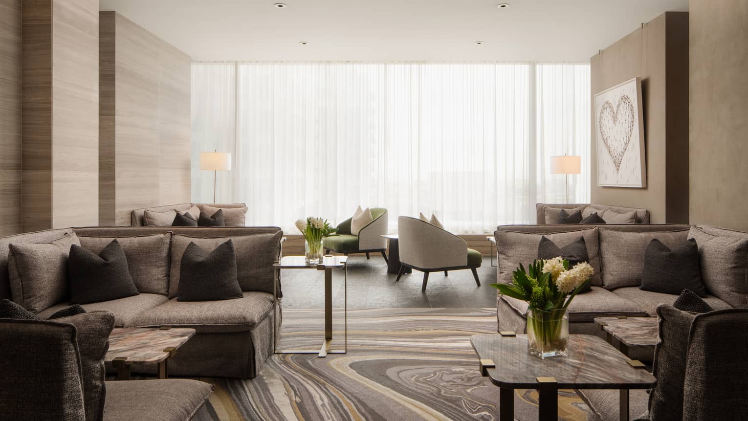 Relaxation lounge with grey sectional sofas and armchairs, marbled coffee tables, floor-to-ceiling windows