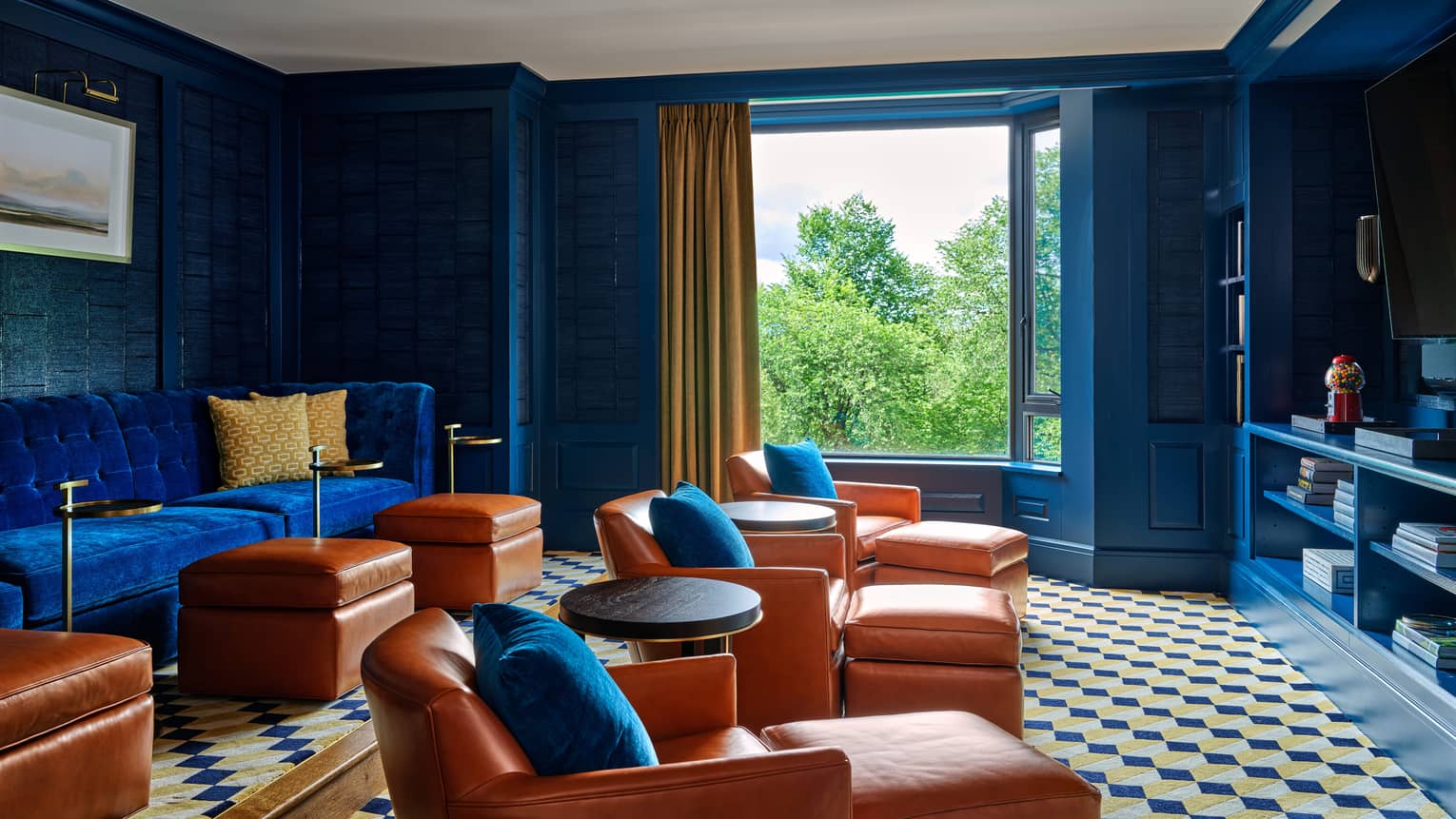 Media room with royal blue walls and sofa, three chaises, and window with tree view ? Royal Suite at Four Seasons Hotel Boston