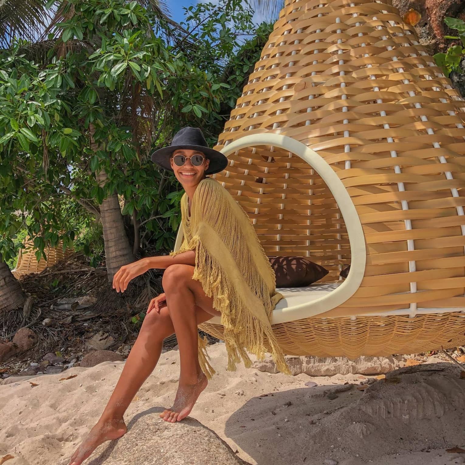 A woman enjoying a serene moment by the beach, on an outdoor wooden swing at Punta Mita