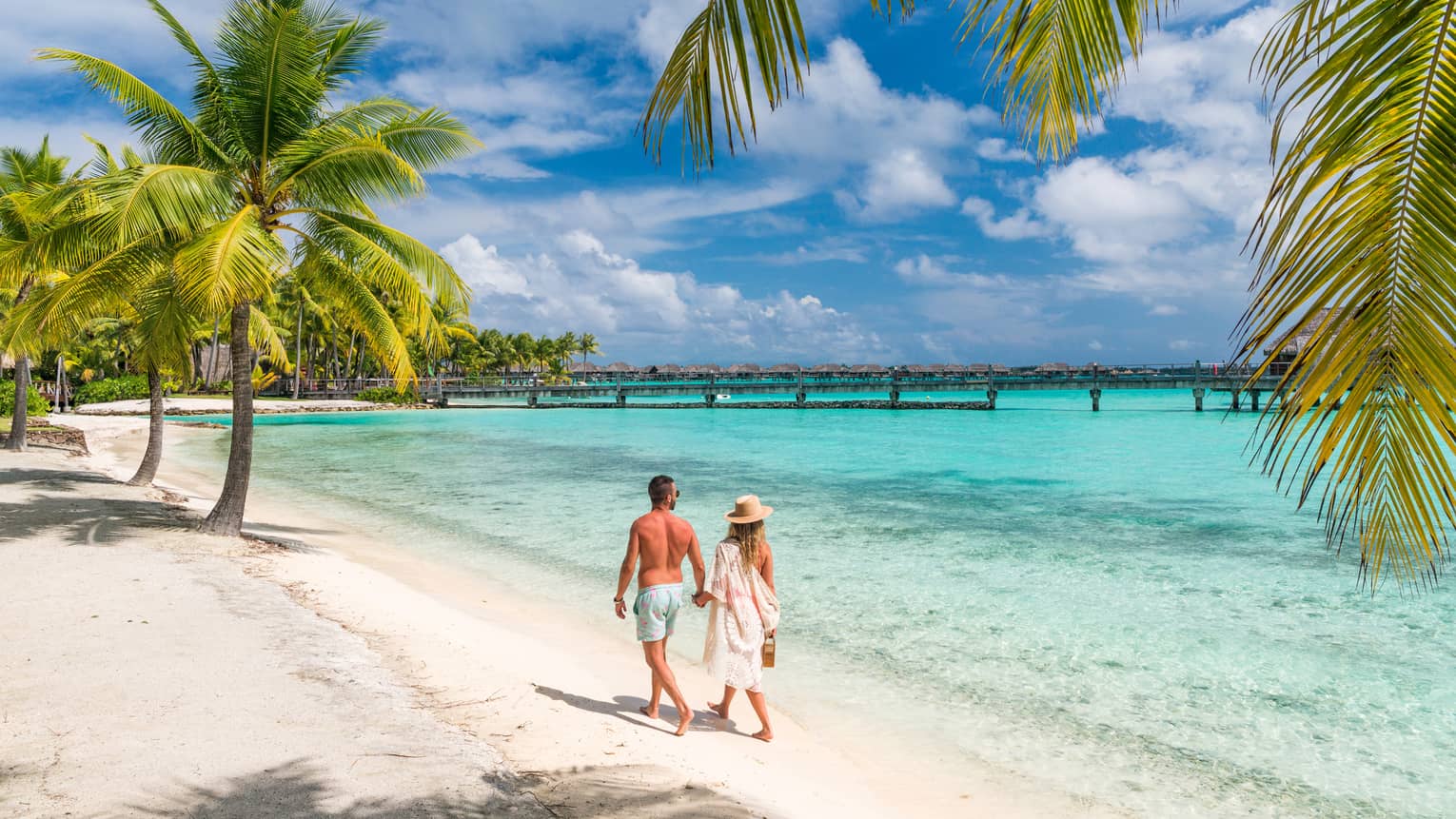 Couple walking on the white-sand beach in Bora Bora
