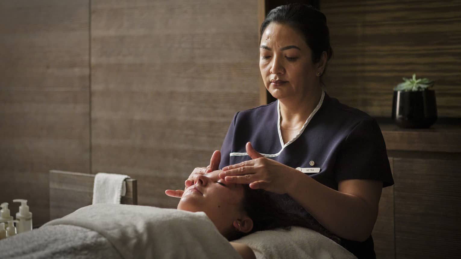 A spa team member giving a facial massage to a guest.
