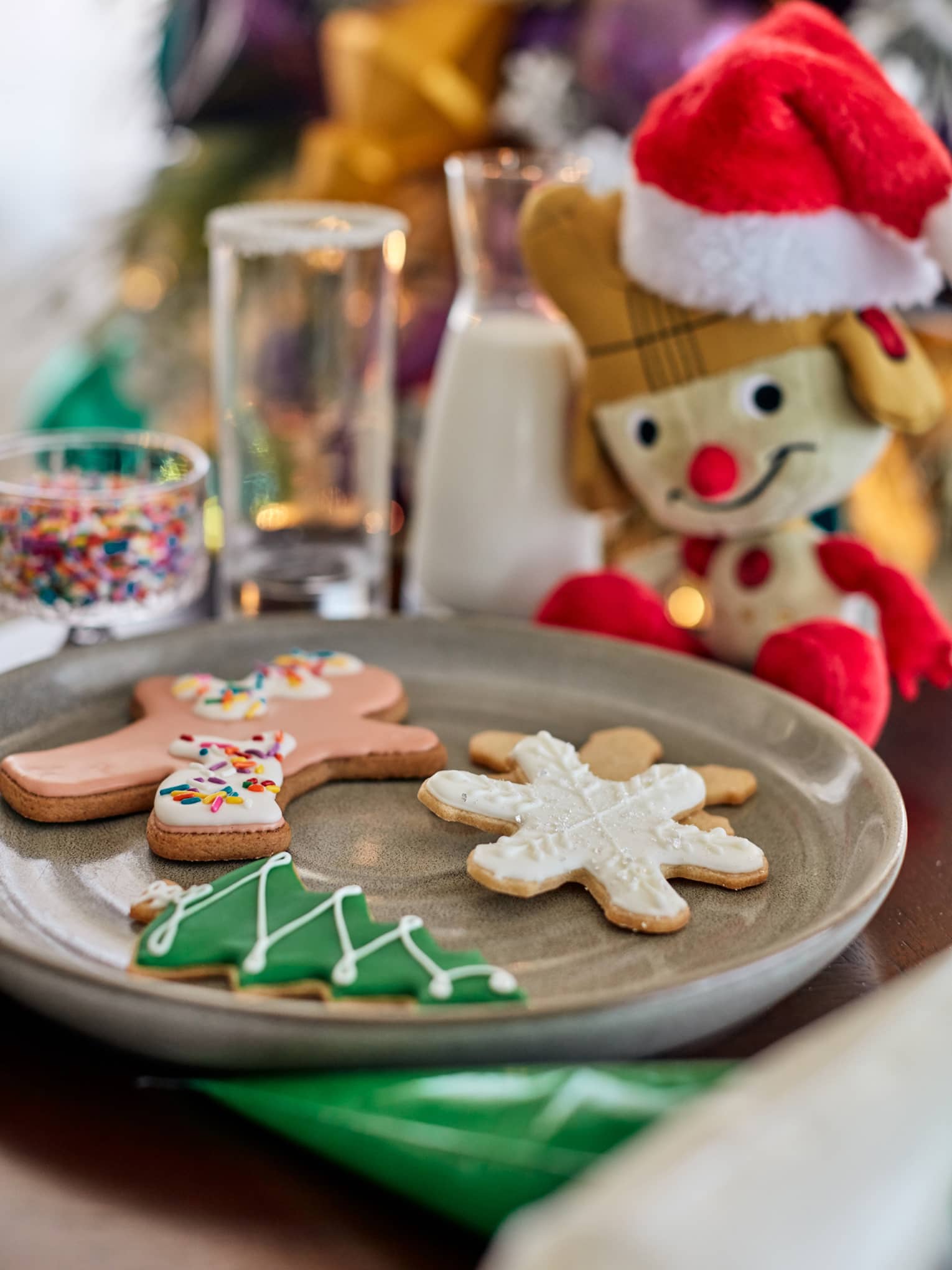 An elf doll next to a plate of cookies.