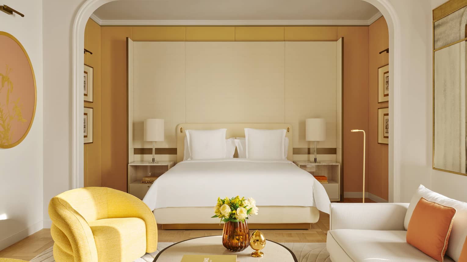 Modern luxury hotel suite with living room leading into bedroom with king bed