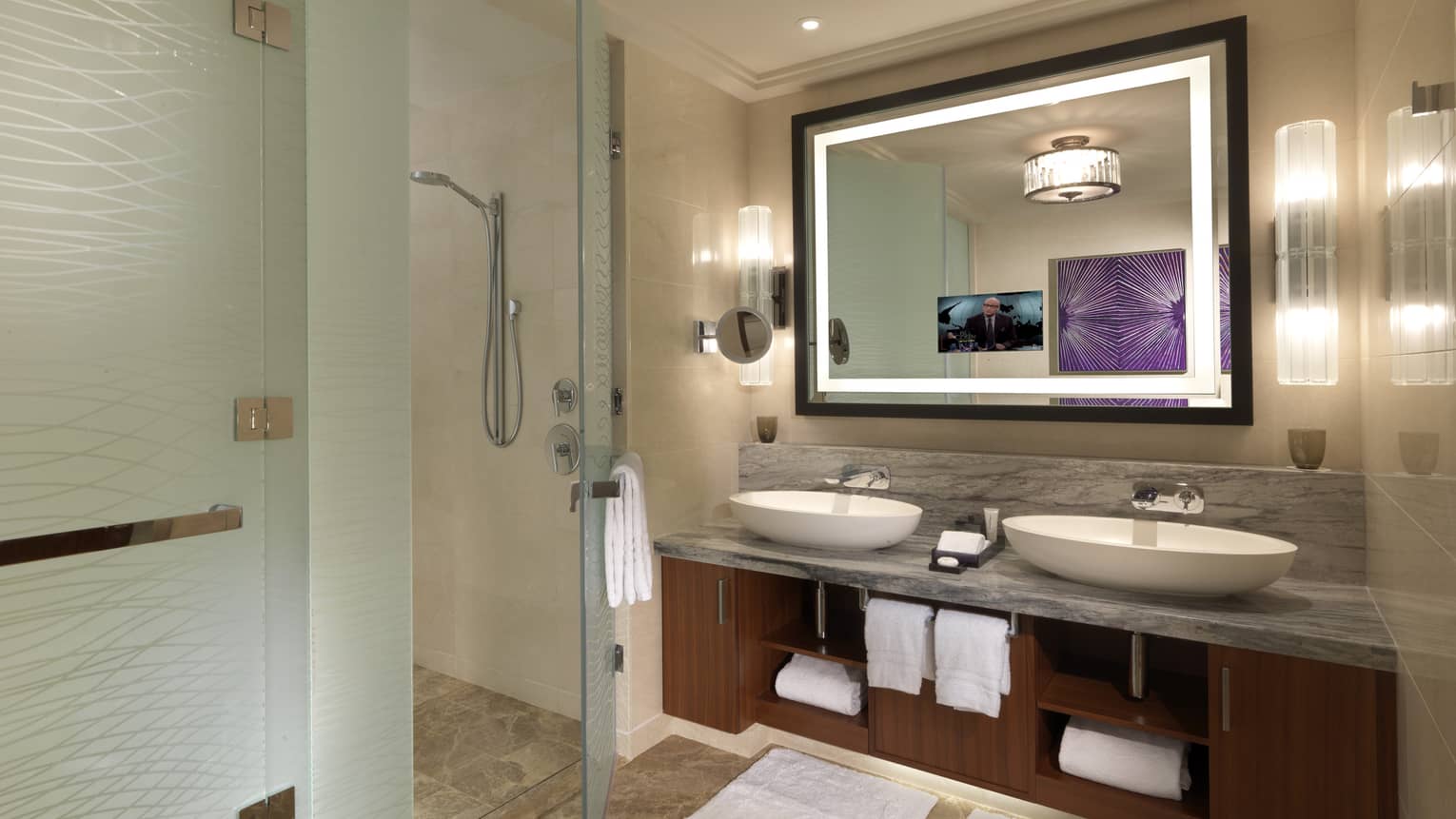 Modern bathroom with dual sinks, a large backlit mirror, glass-enclosed shower, marble countertop and purple wall art