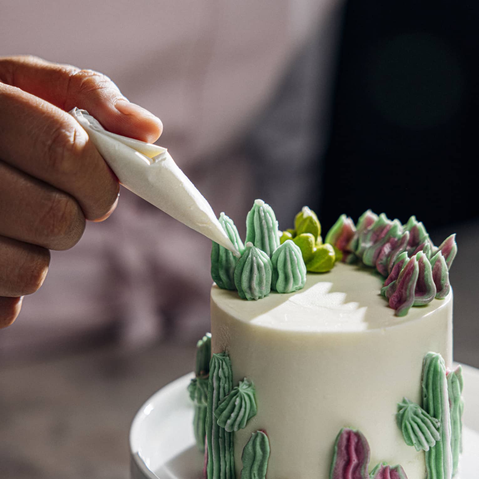 Person decorating a cake with green icing.