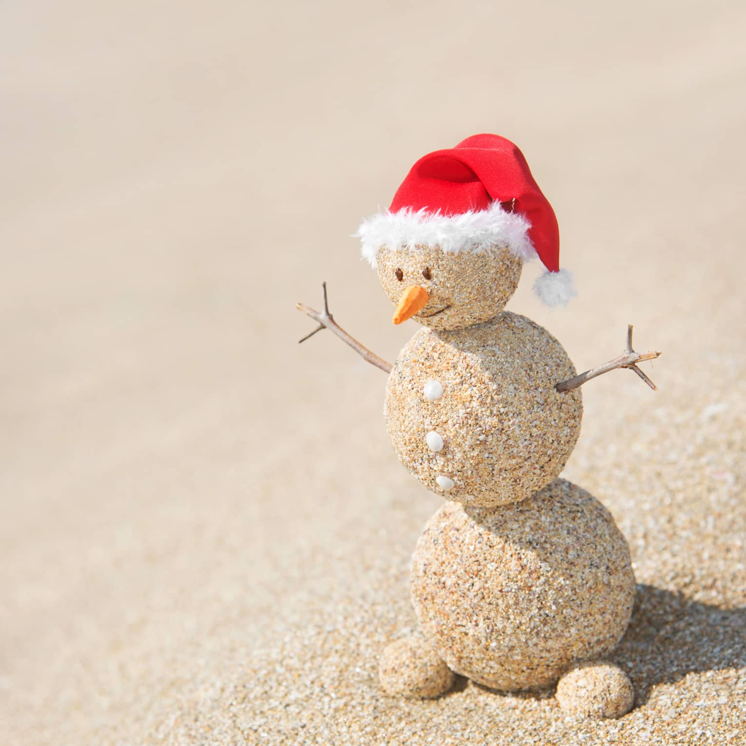 A snowman made out of sand with a red Santa hat.