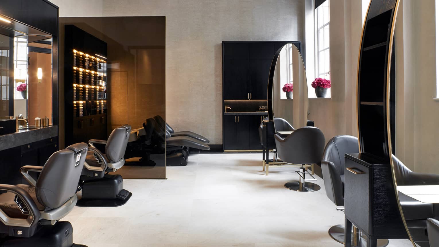 A spacious salon space with soft natural light from large windows, and decor in serene neutral hues