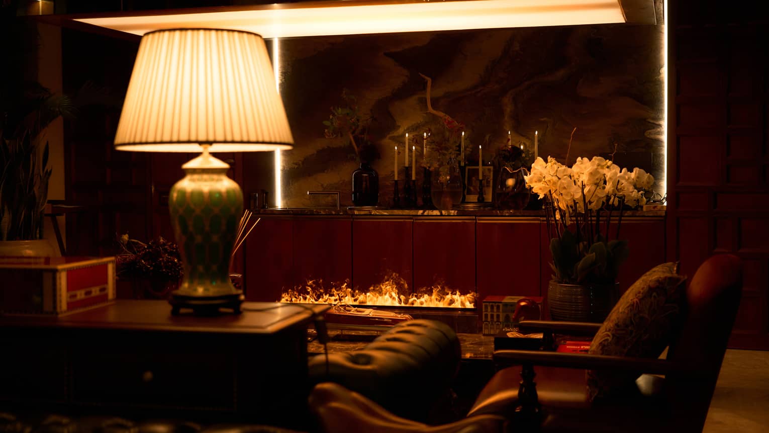 Restaurant lounge area with large lamp, arm chairs and an open-flame fireplace
