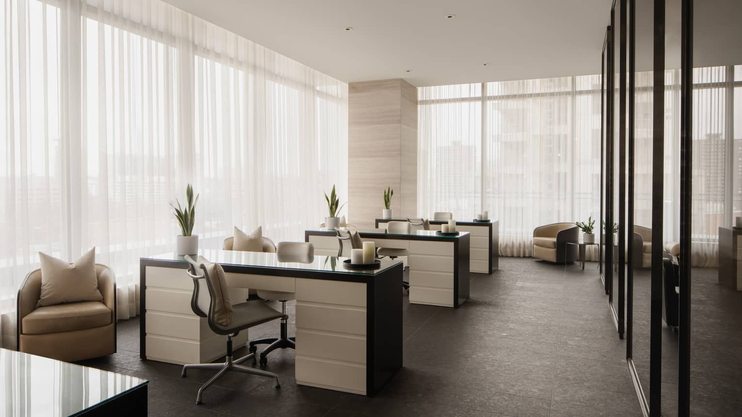 Nail salon with three black and white stations, floor-to-ceiling windows with sheer white curtains