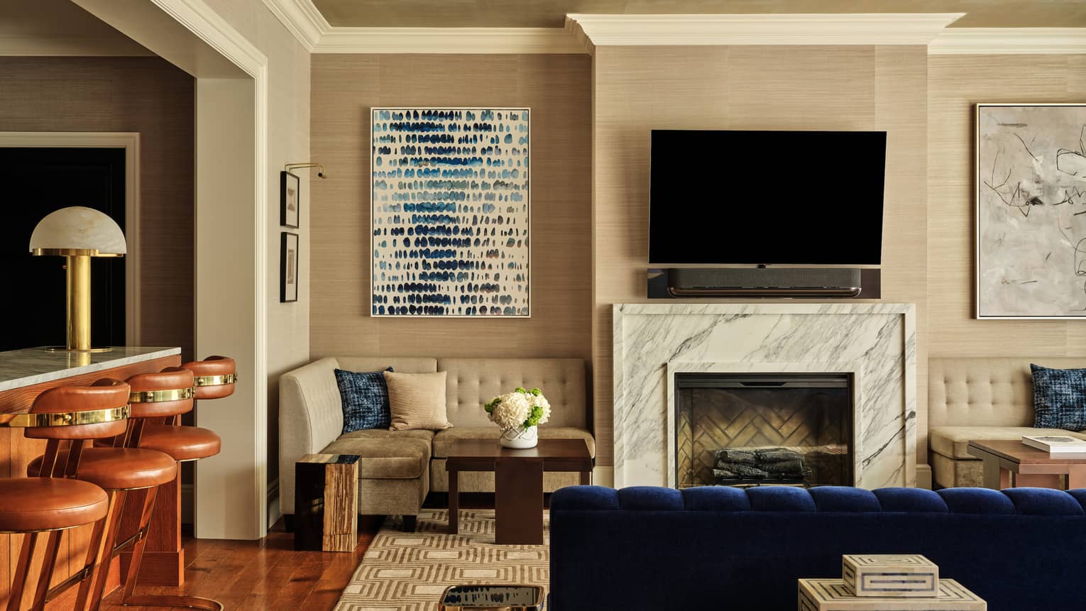 Stylish Royal Suite at Four Seasons Hotel Boston, showing a living room with royal blue velvet sofa and three tan bar seats at island counter