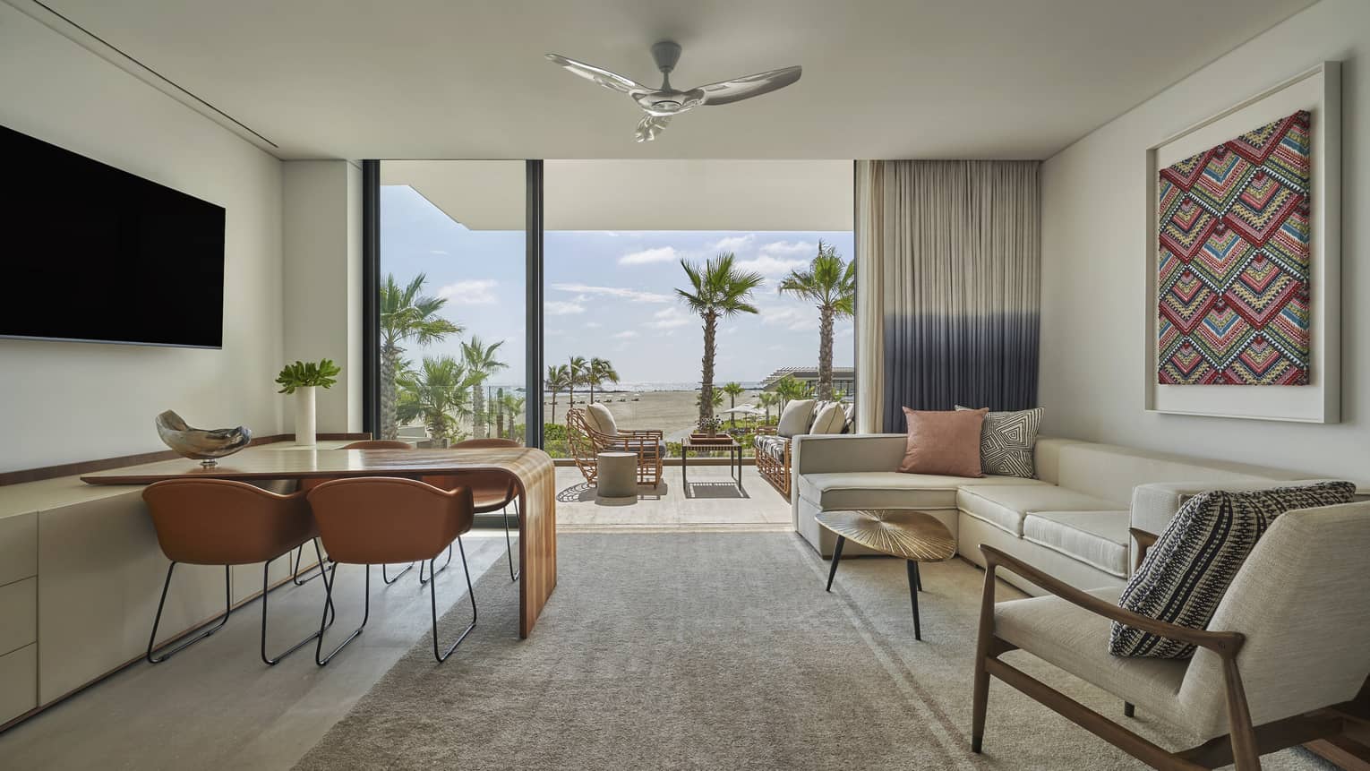 Living room with dining table for four, cream-coloured l-shaped sofa, walk-out balcony