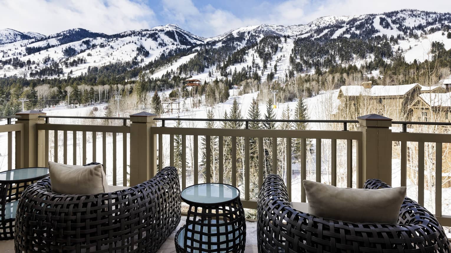 Mountain-view balcony with two wicker chairs and small table