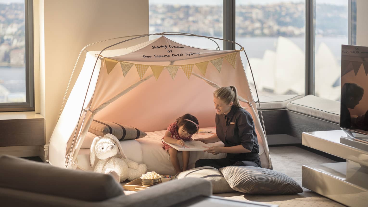 Little girl colours with help of FS staff member in an in-room tent
