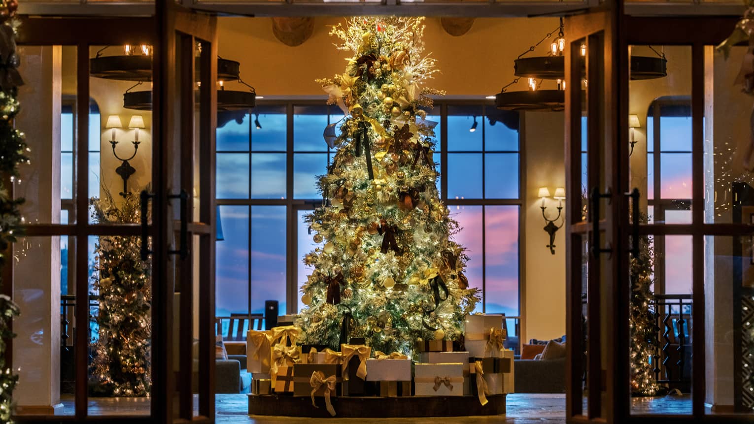 A tree decorated with lights and ornaments and surrounded by presents
