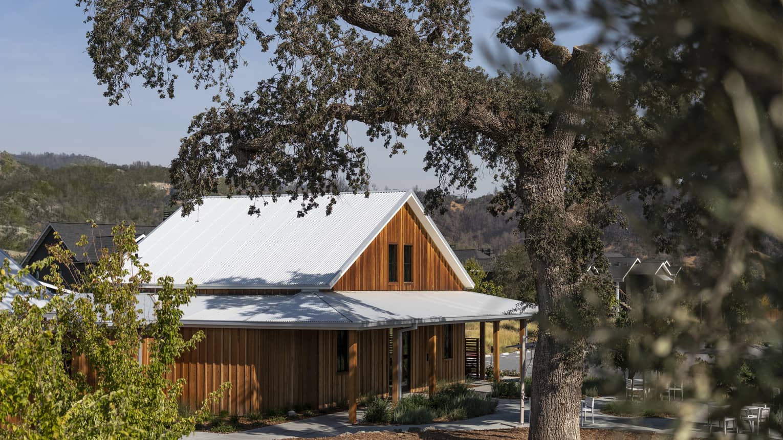 A wood building behind trees and surrounded by plants.