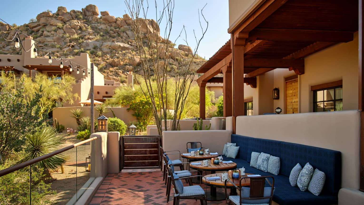 Outdoor terrace with booth seating and chairs and a view of the mountains.
