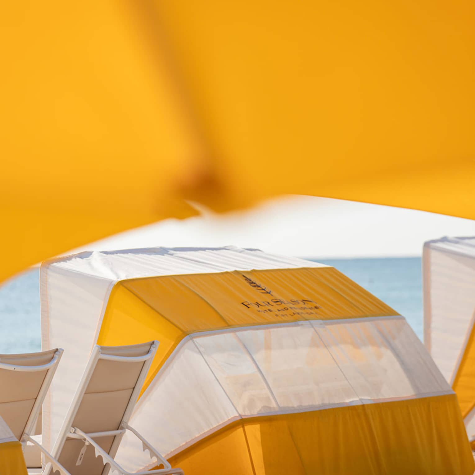 A daybed on the beach with lounge chairs