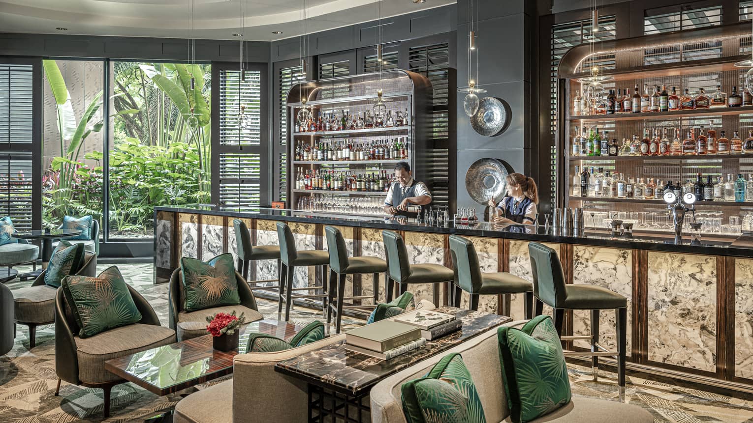 Male and female bartender stand behind counter at light-filled One-Ninety Bar