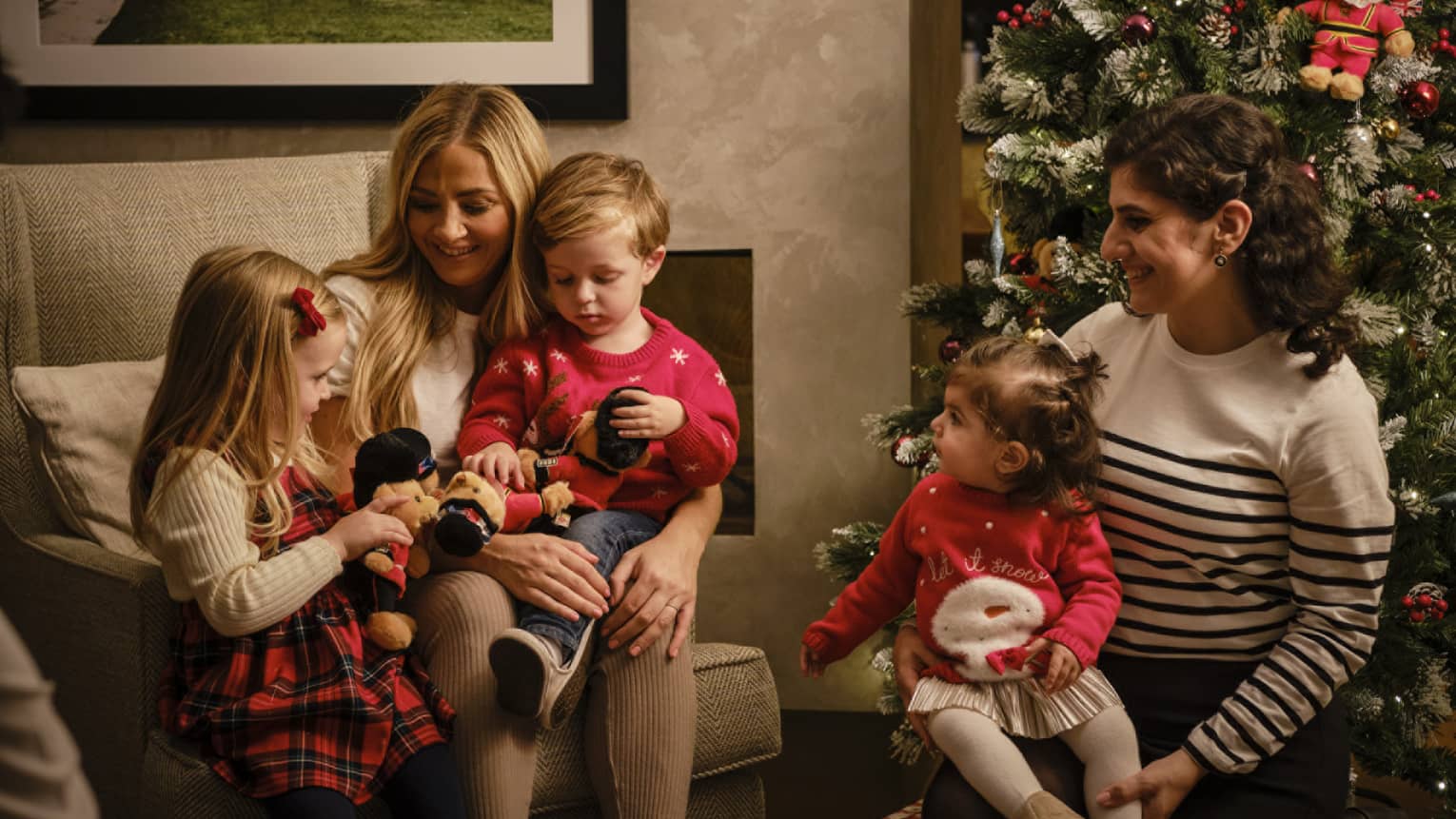 Family of five dressed for the holidays, seated and gathered around a Christmas tree