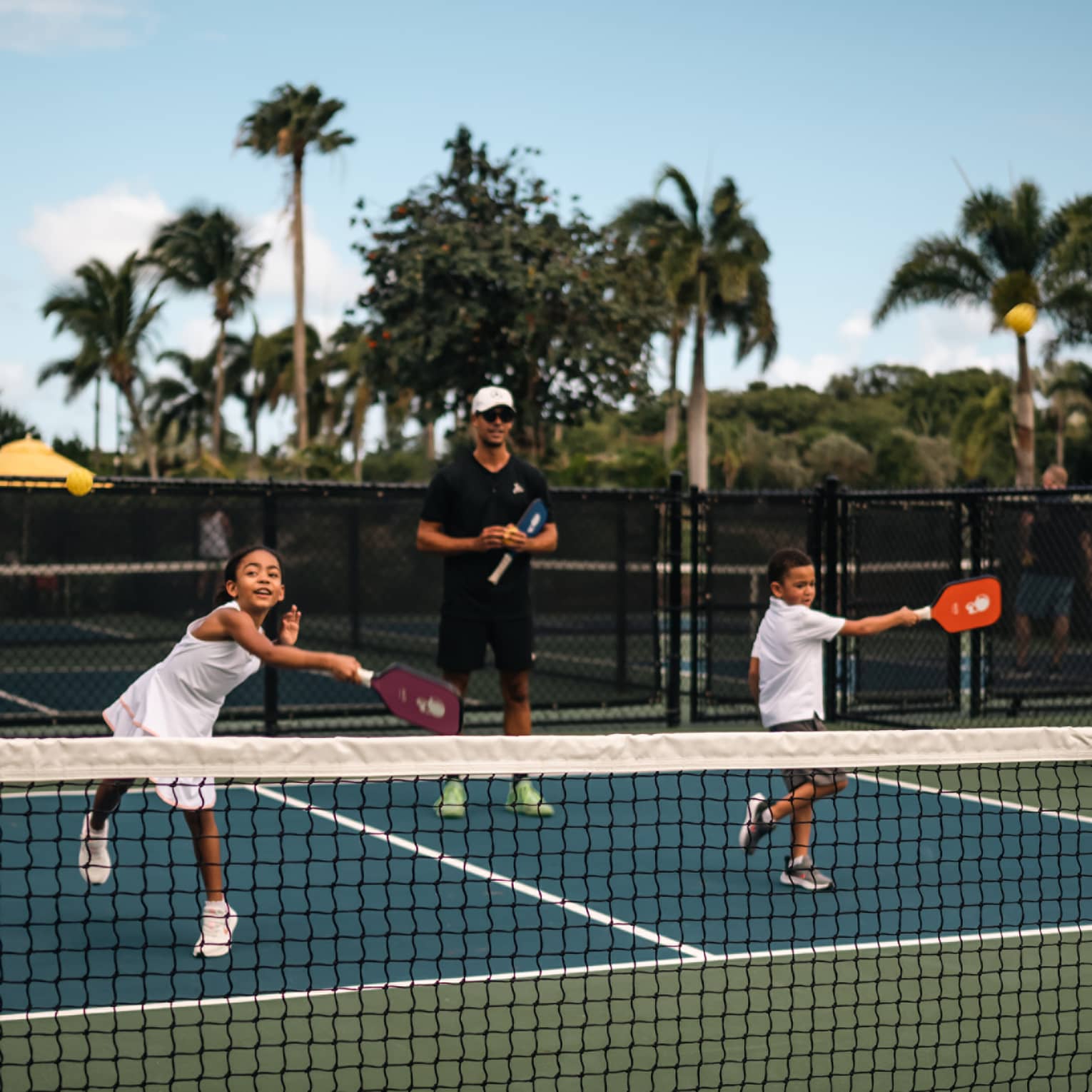 Two young children playing pickleball on a court.