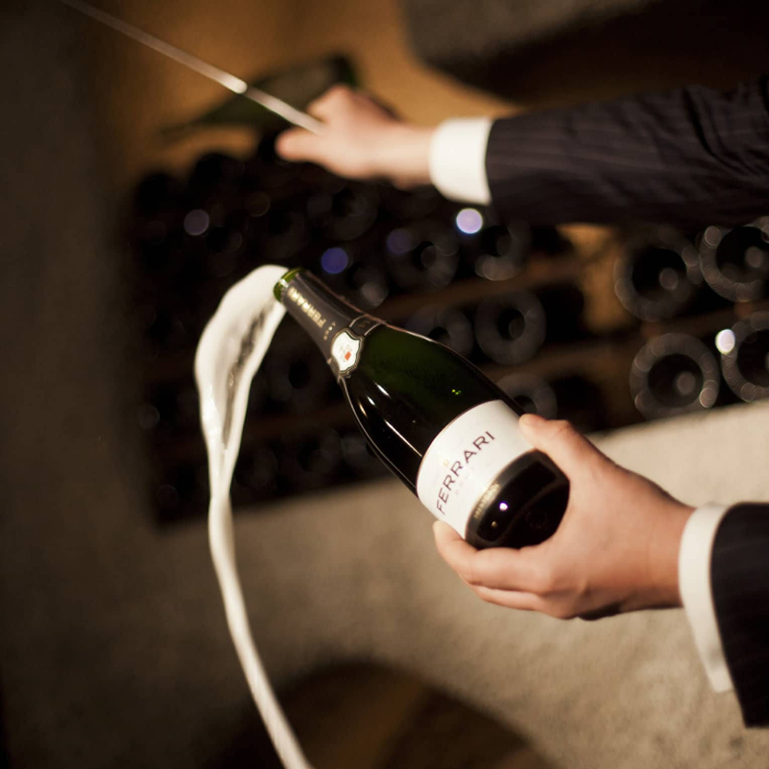 Person pouring champagne out of a champagne bottle.