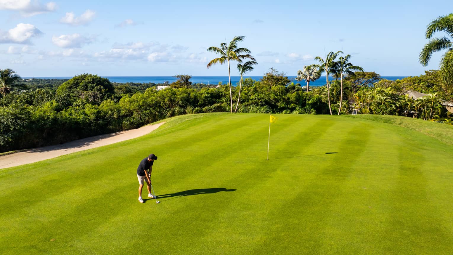 A person playing golf on a golf course near the ocean