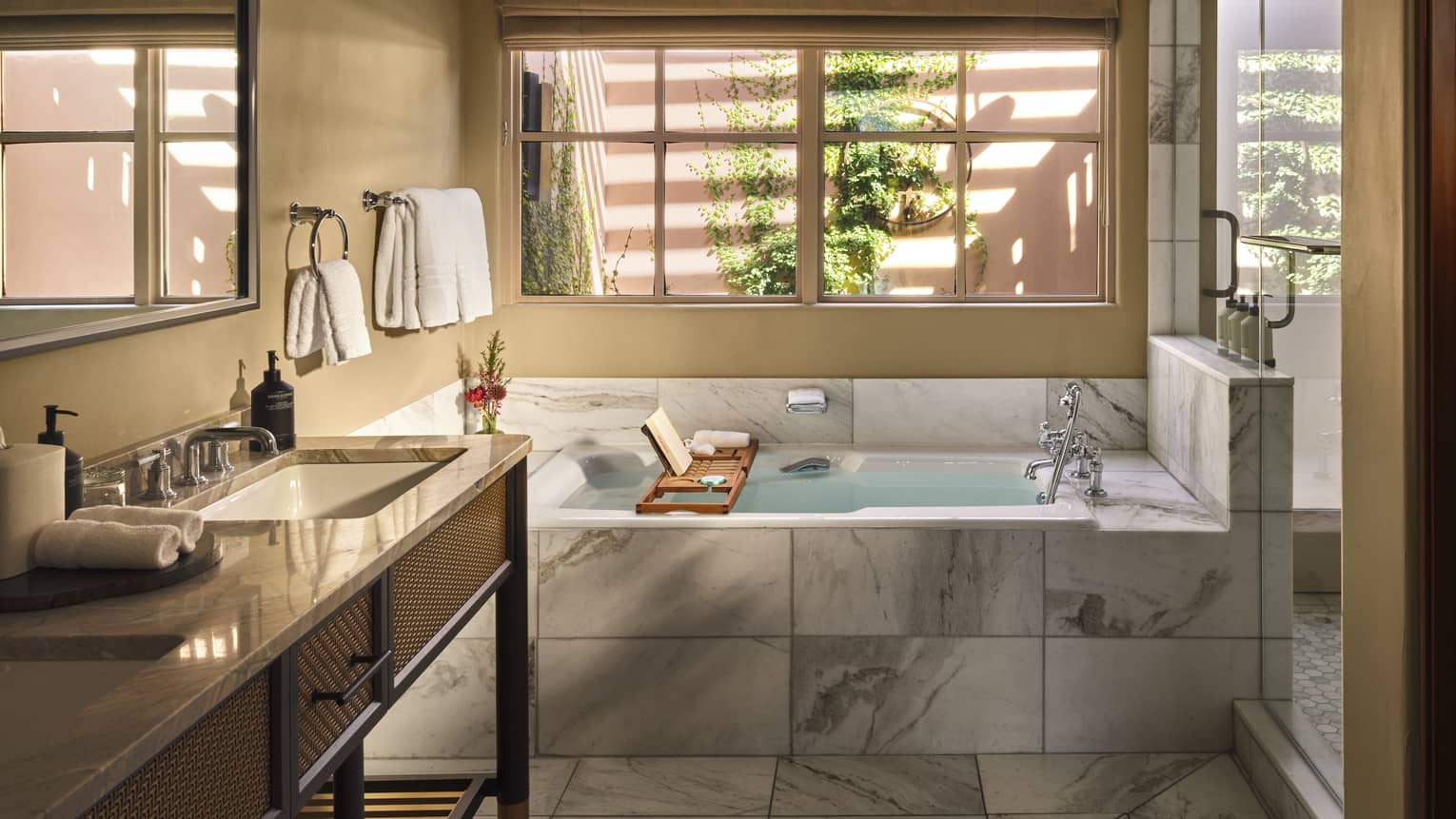 Contemporary bathroom featuring marble tile floors and deep soaking tub, a window and a double vanity