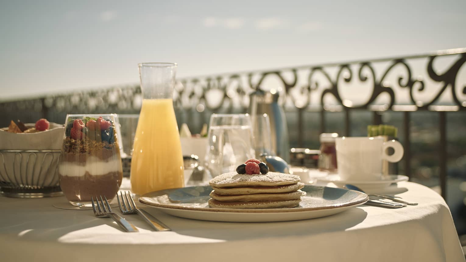 Breakfast set up on a white-cloth round table on hotel balcony