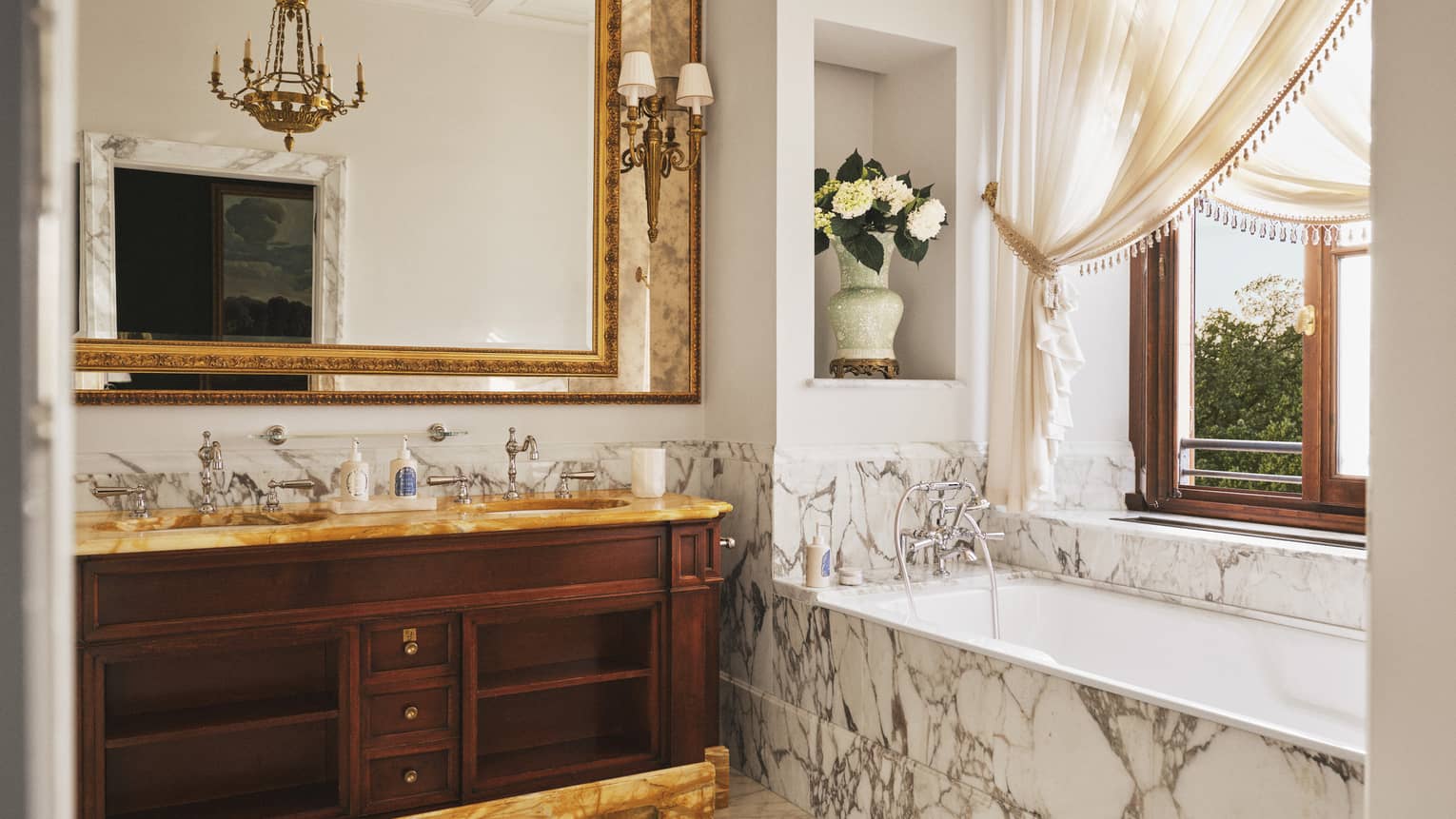 Suite bathroom with marble floors and tub, ornate double vanity and window, at Four Seasons Hotel Florence