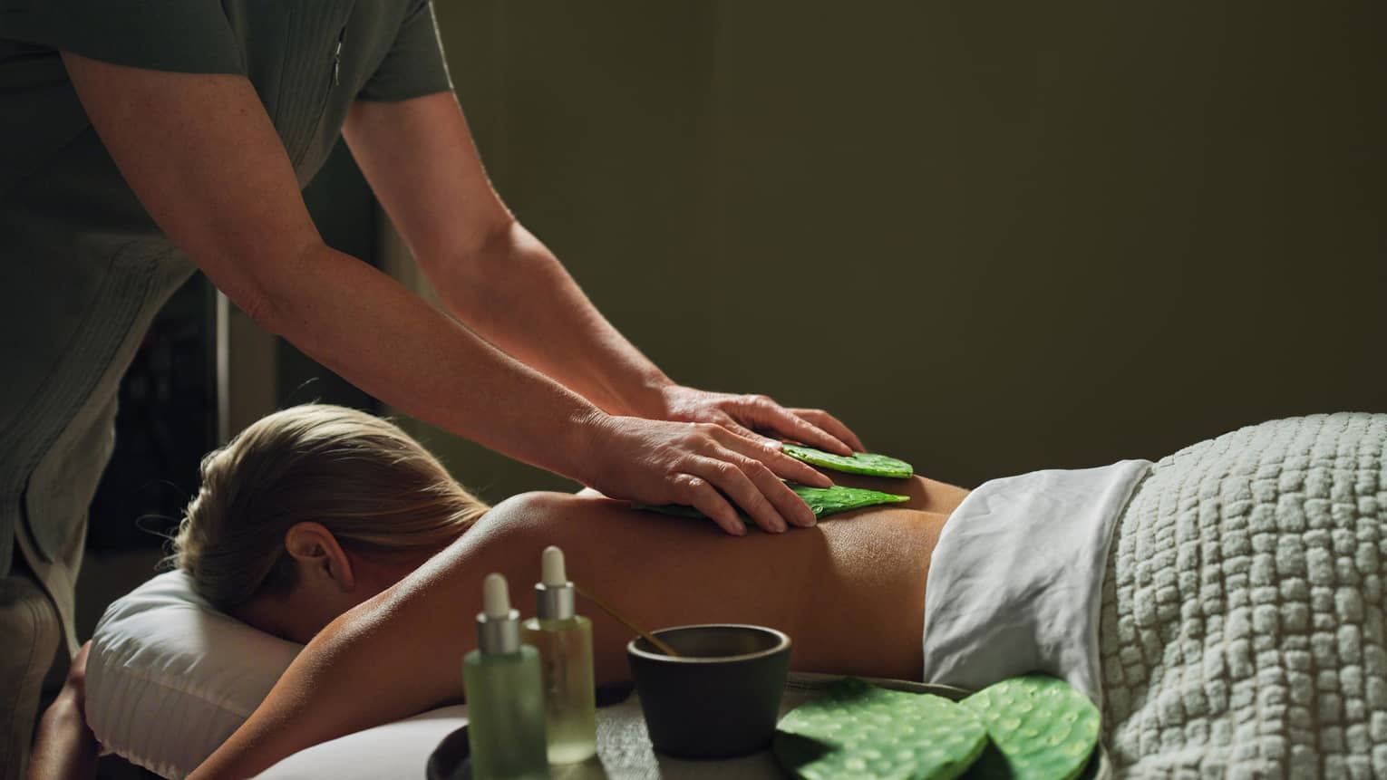 Guest laying on massage table with a blanket while getting a back massage.