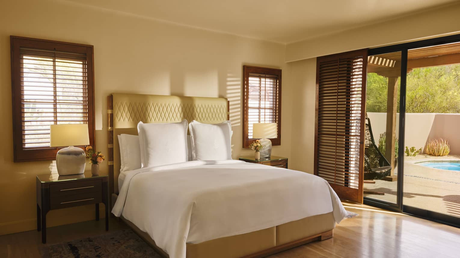 Sunlight streams into bedroom with wooden floors, king bed and walk-out terrace to a plunge pool