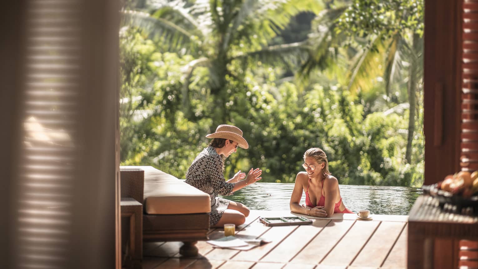 Two guests relaxing and conversing in an outdoor pool in Bali