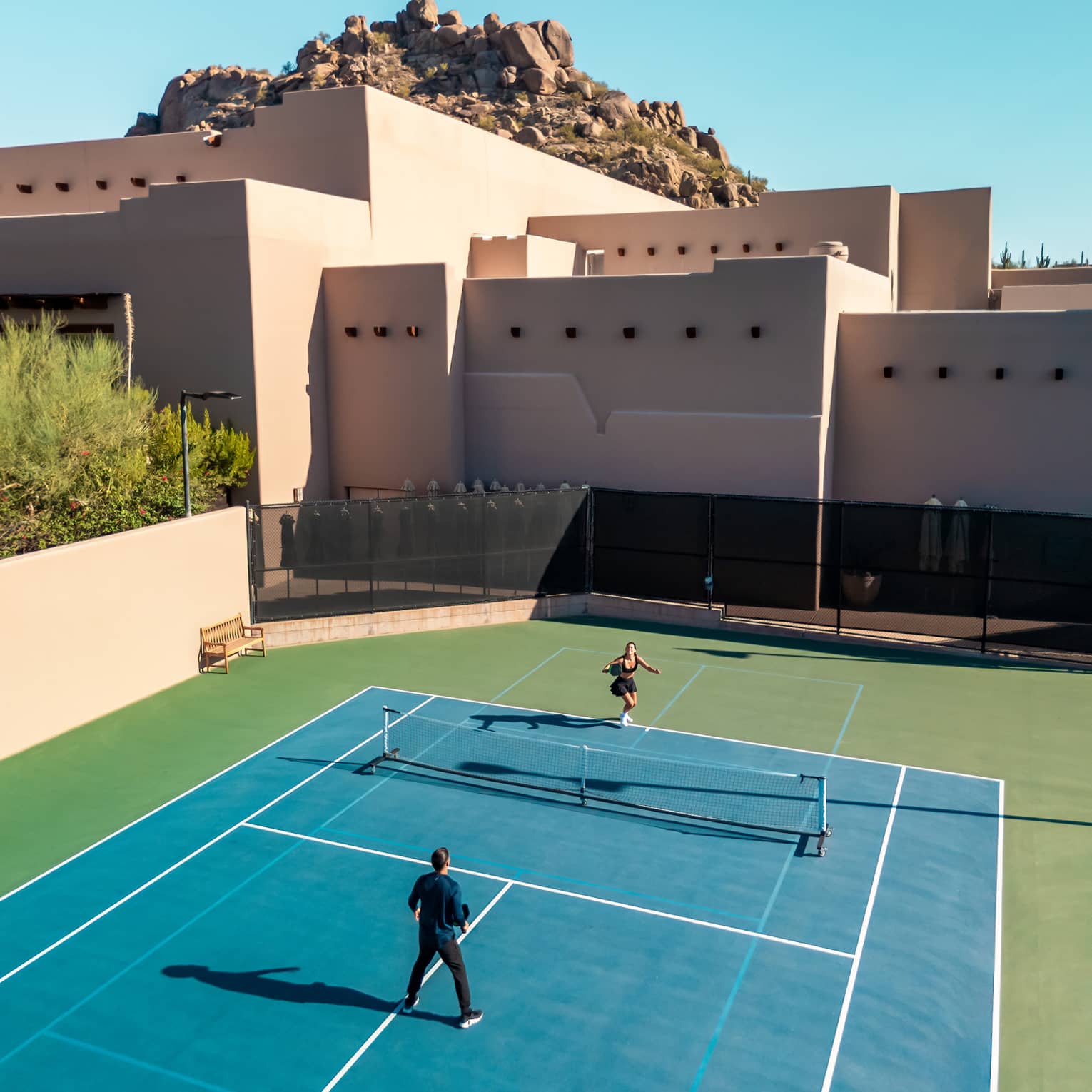 Aerial view of two guests playing a game of tennis.