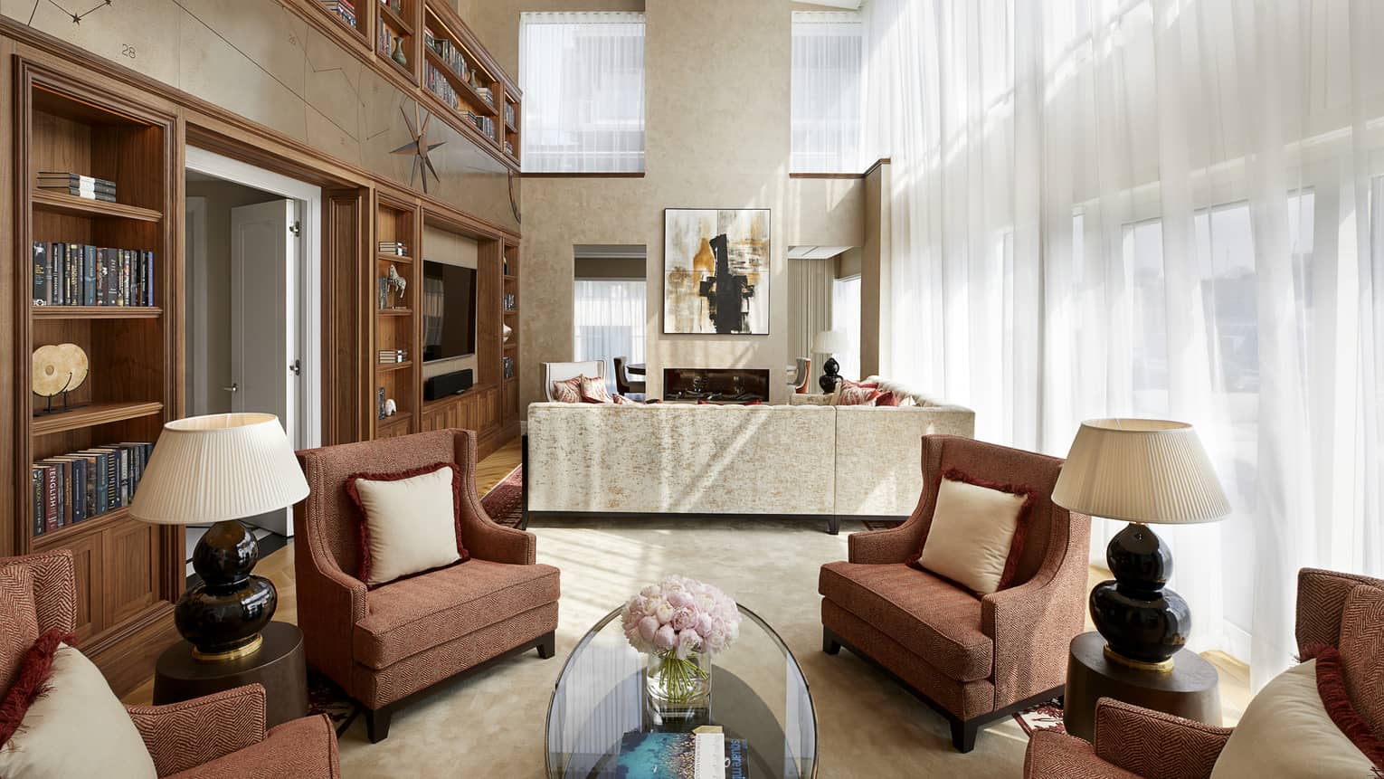 Armchairs, table and lamps under high loft ceilings in front of seating area, sofa