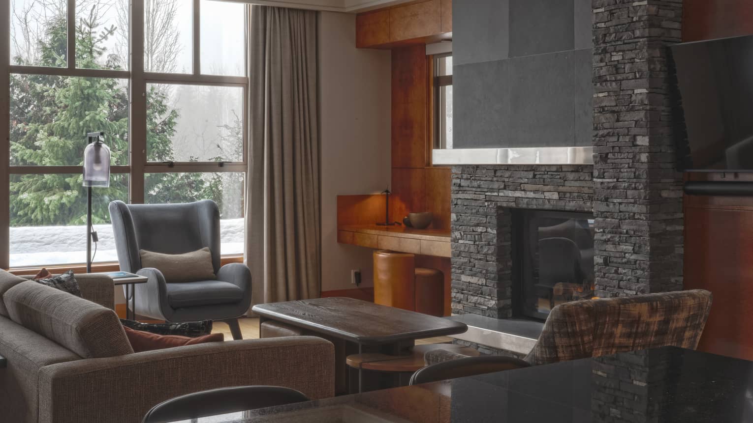 Contemporary living room of a private residence, with charcoal-coloured sofa and stone fireplace