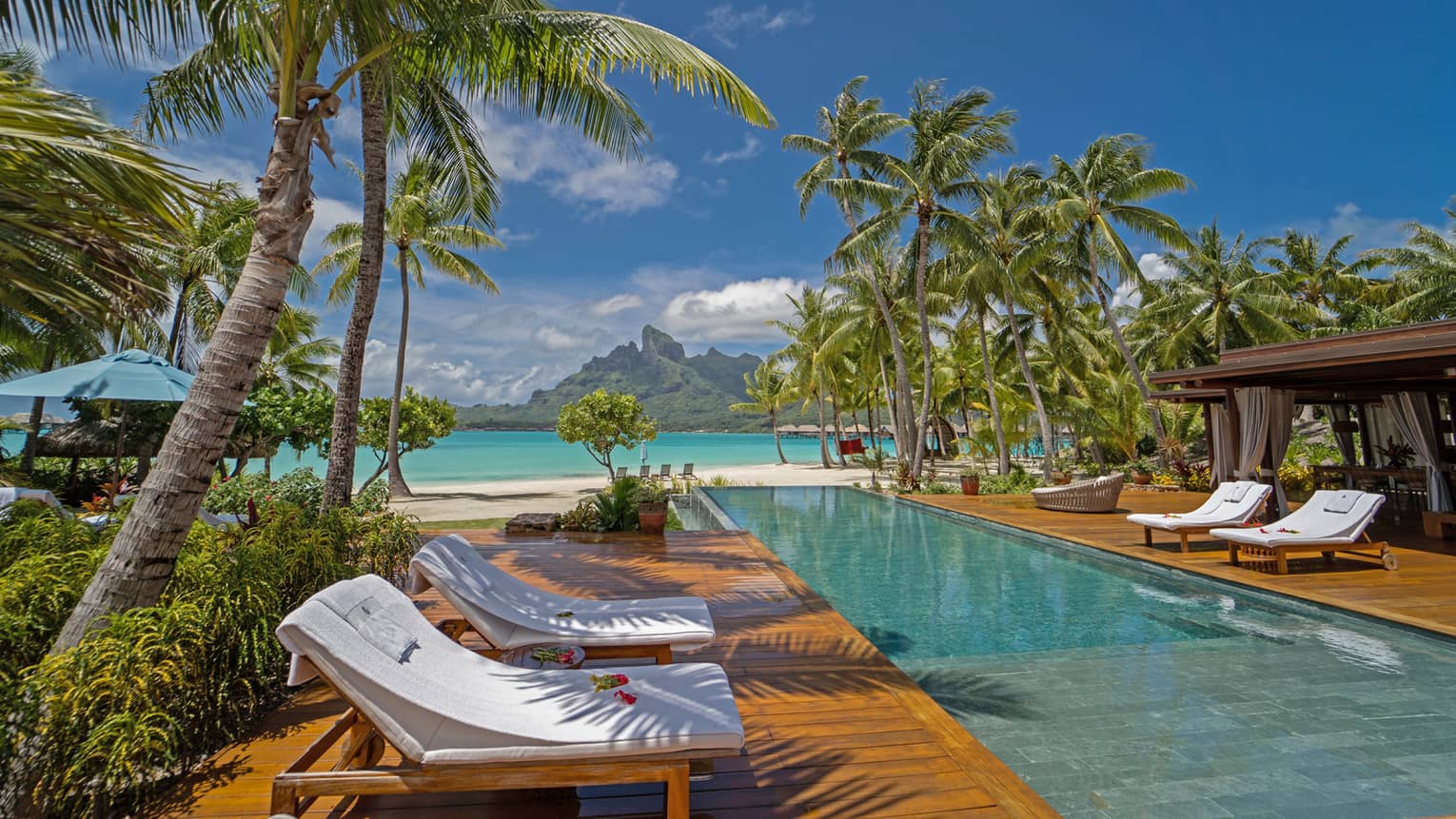 Long rectangular pool with lounge chairs in Bora Bora villa, with view of turquoise lagoon
