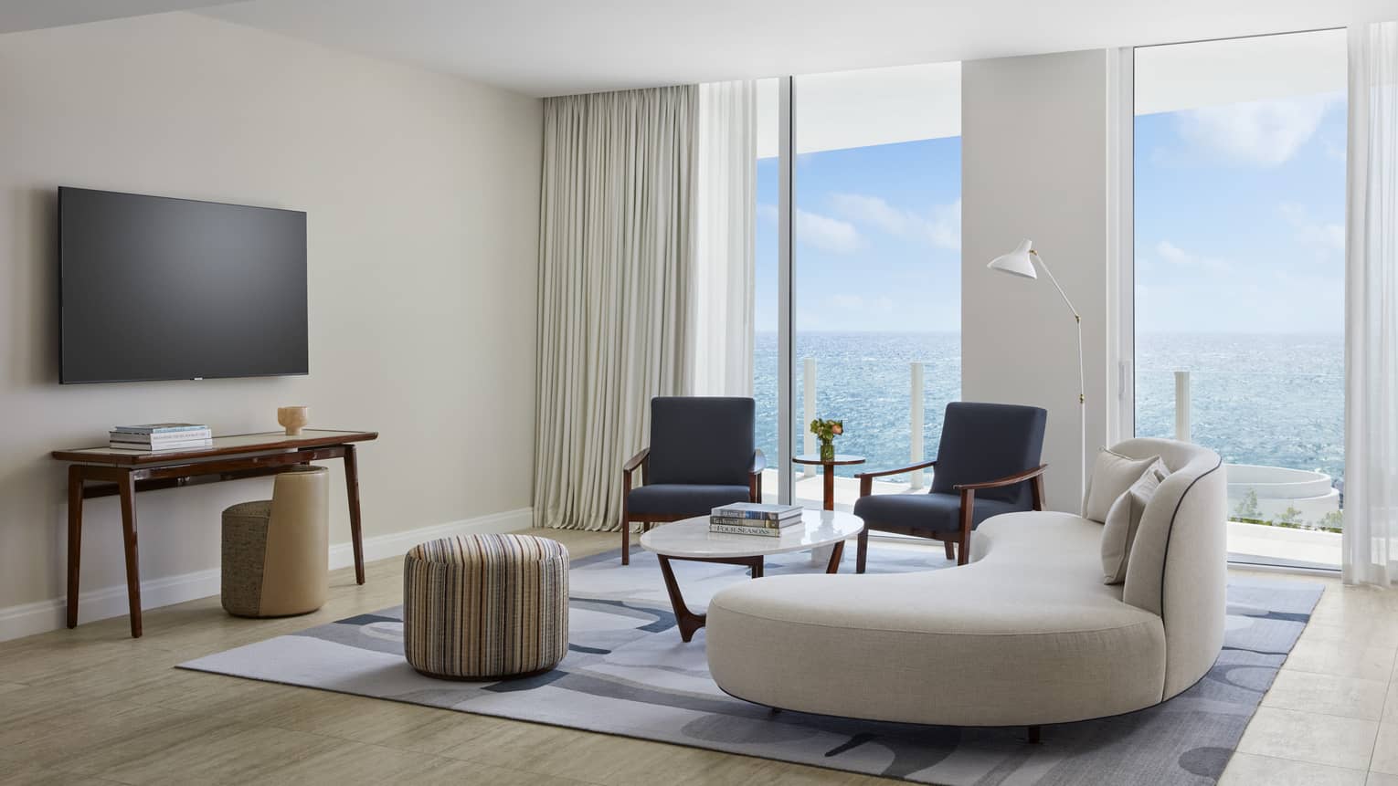 Ocean-view living room with low, curved sofa and two chairs