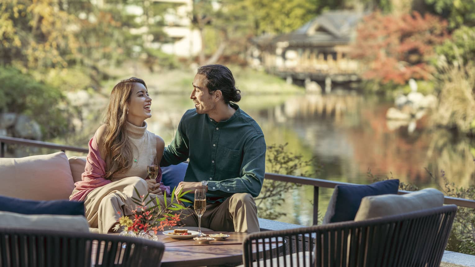 Couple enjoys light snacks and champagne on lounge chair with views of the pond garden