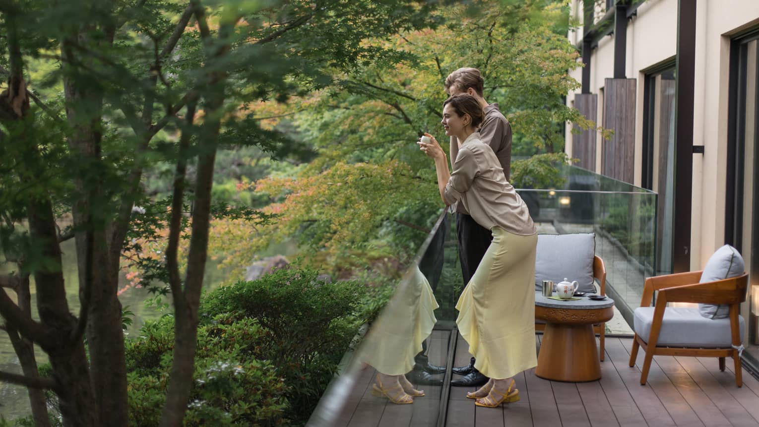 Two people enjoying a peaceful moment on a balcony surrounded by lush green trees at Four Seasons