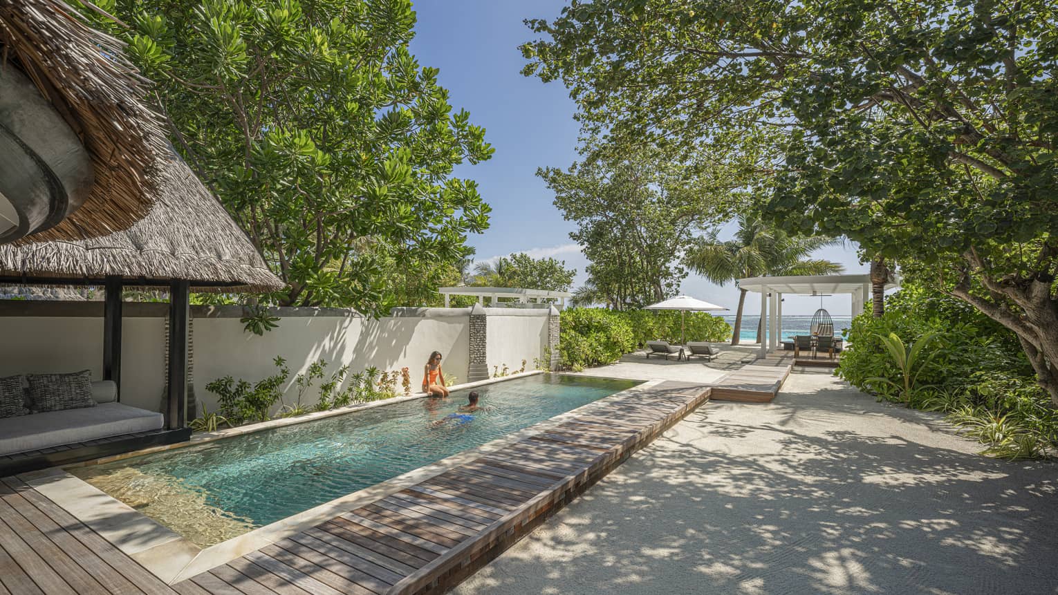 Private rectangular pool in a tropical villa setting with ocean in the distance