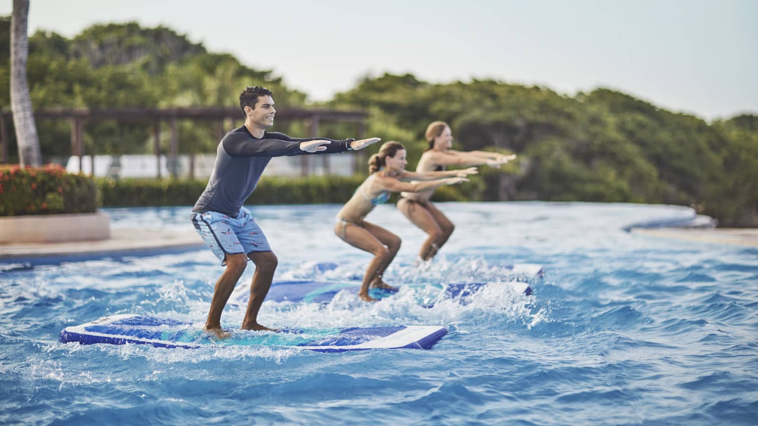 Two guests being instructed how to stand up on surf boards