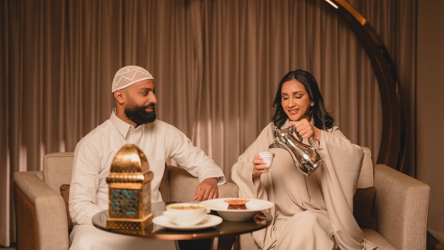 A couple sits at a bistro table enjoying coffee and pastries