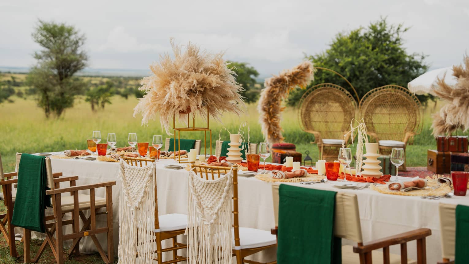 Long banquet table set with green and orange d�cor and natural grass arrangements on a plain