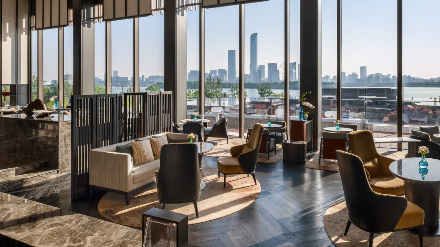 The Lounge and Bar lounge seating at Four Seasons Hotel Suzhou. Heigh-ceilinged walls of windows look out to lake and city centre.