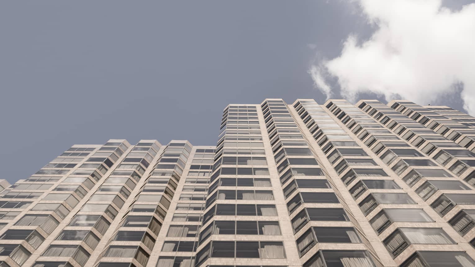 View of the sky and a tall building with many windows.