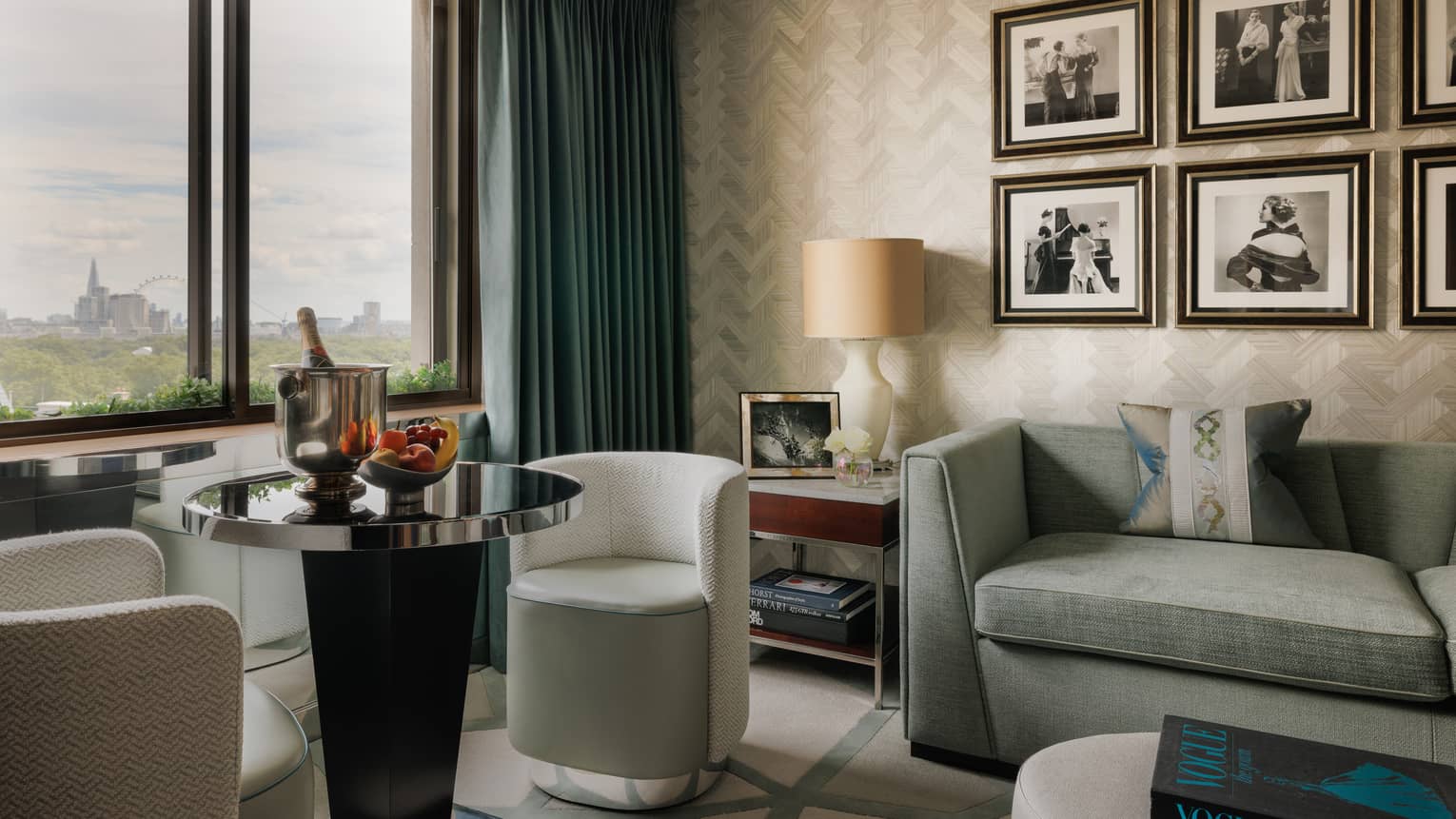 Luxury hotel suite at Four Seasons Hotel London at Park Lane, featuring a stylish living room with a sofa, round table with two chairs and six framed photos on the wall