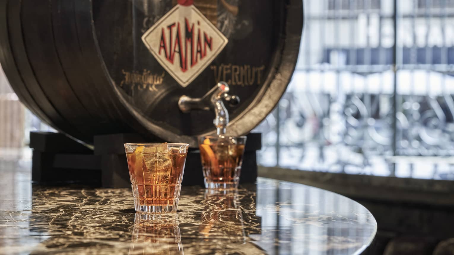 Vermouth cask with two filled cocktail glasses on marble table