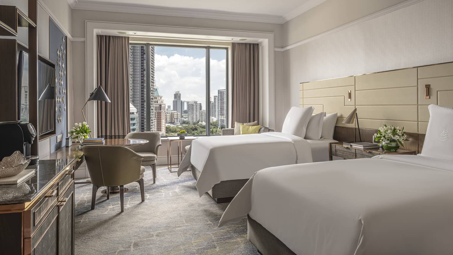 Hotel room with two twin beds, small table and two chairs, window of Singapore city