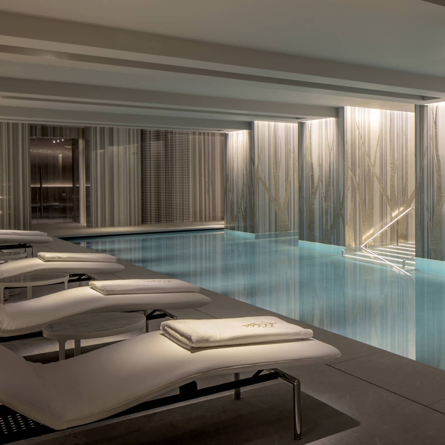 View of indoor serenity pool with illuminated classic columns and blue water